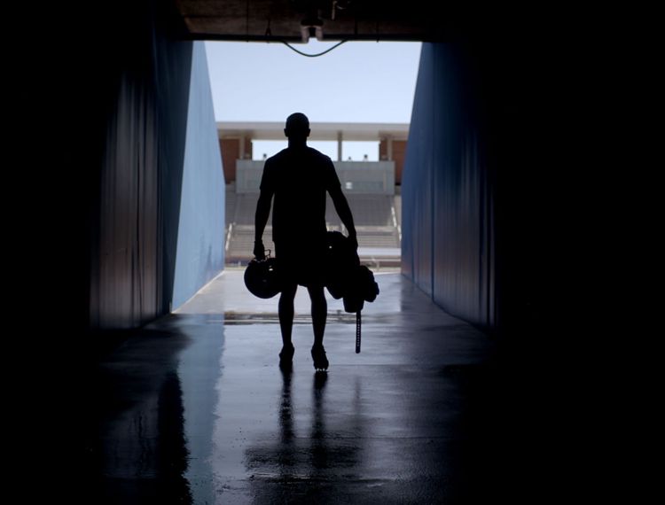 silhouette of player carrying gear entering stadium