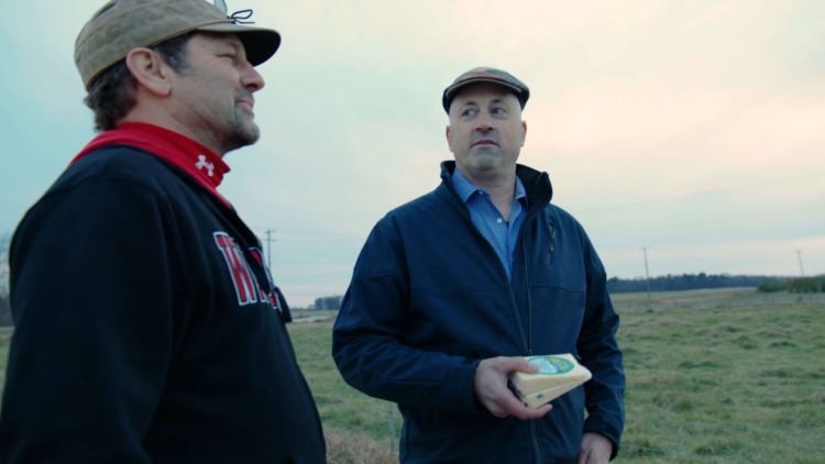 Ken McNulty in field with package of cheese