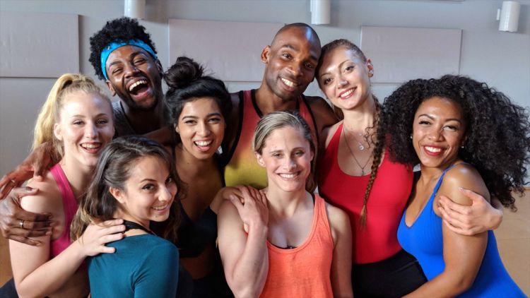 A group of dancers huddled together and smiling for the camera.