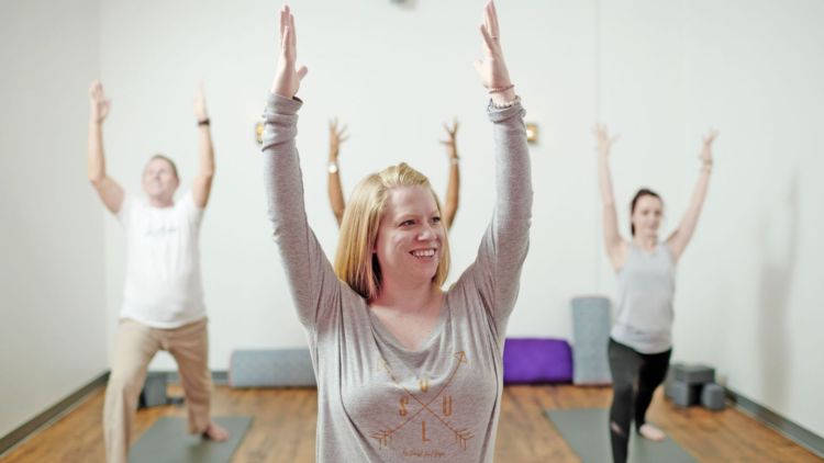 Suzie Mills with arms raised instructing yoga