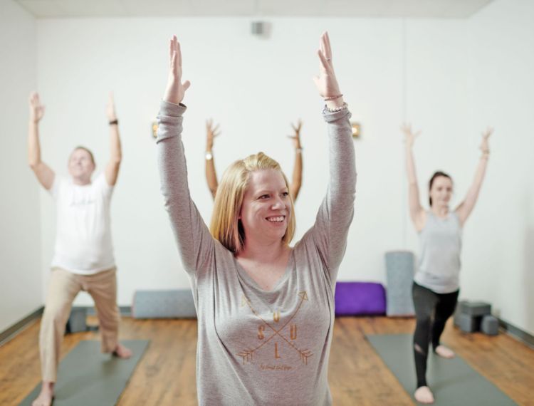 Suzie Mills with arms raised instructing yoga